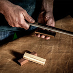 Person working on a leatherwood item with tools on a leather surface
